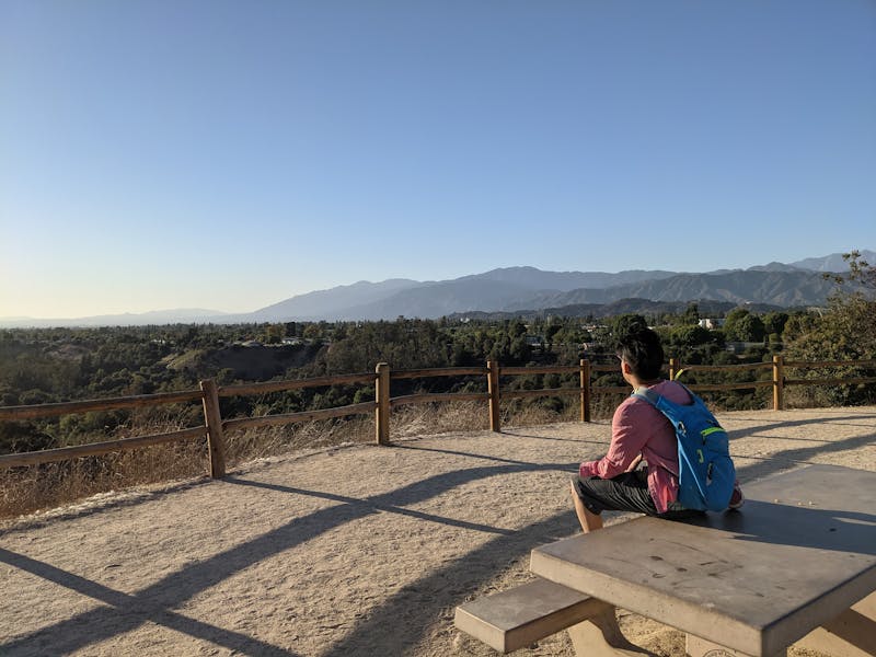 Hiker sitting at a picnic table overlooking the mountains at The Antonovich Trail in San Dimas 