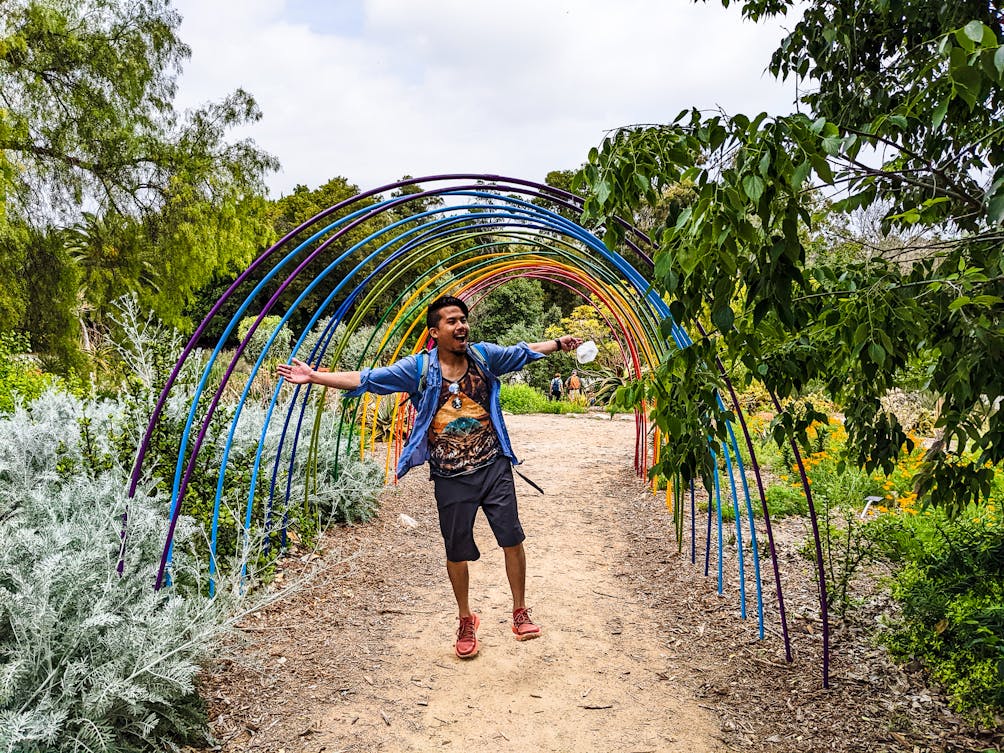 Young person smiling under rainbow arches in South Coast Botanic Garden in Rancho Palos Verdes  