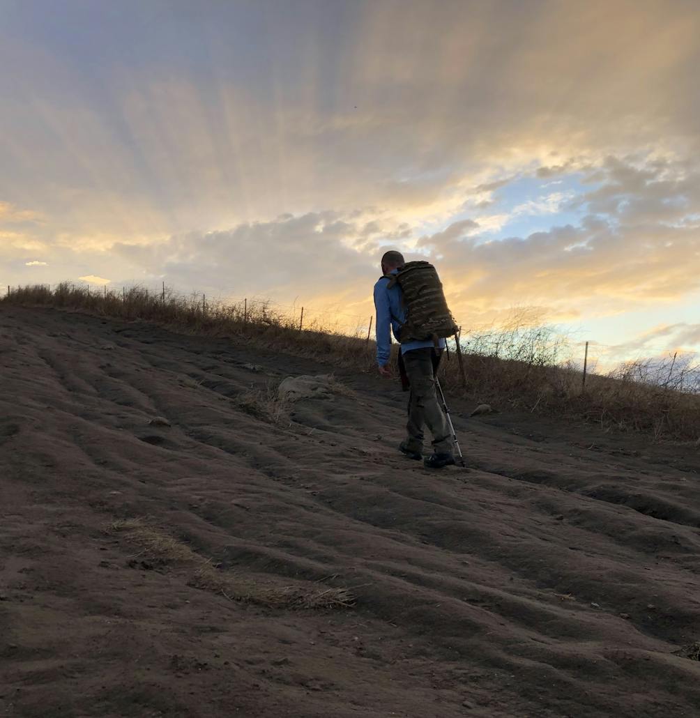 Hiker going up a trail towards Mission Peak at sunset 