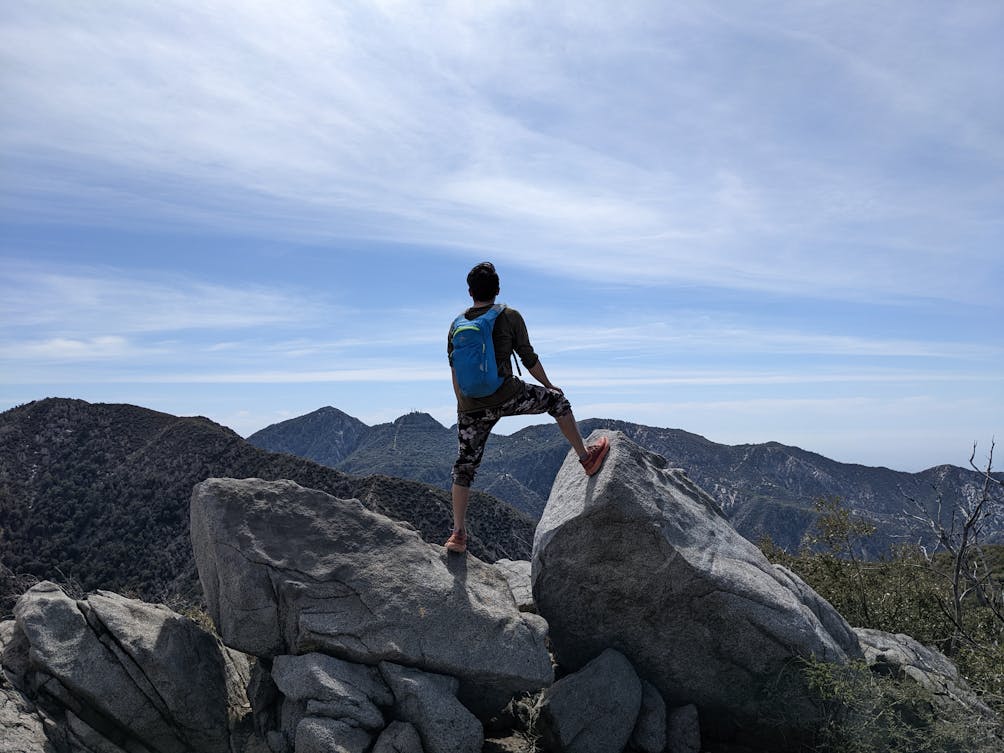 Hiker on a rock looking out to the surrounding San Gabriel Mountains at Strawberry Peak 