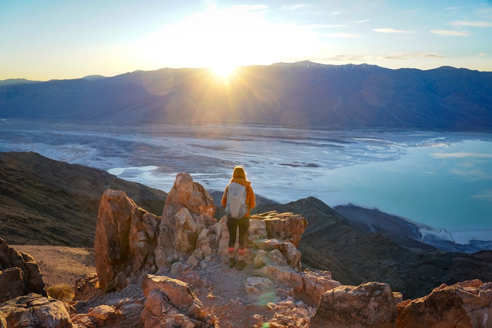 A woman stands at Dante's View in Death Valley, looking out to Telescope Peak and Manly Lake, Badwater Basin below. 