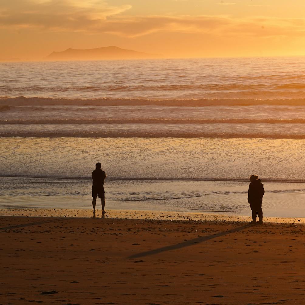 Two people watching the sun set behind Channel Islands National Park from Hollywood Beach 