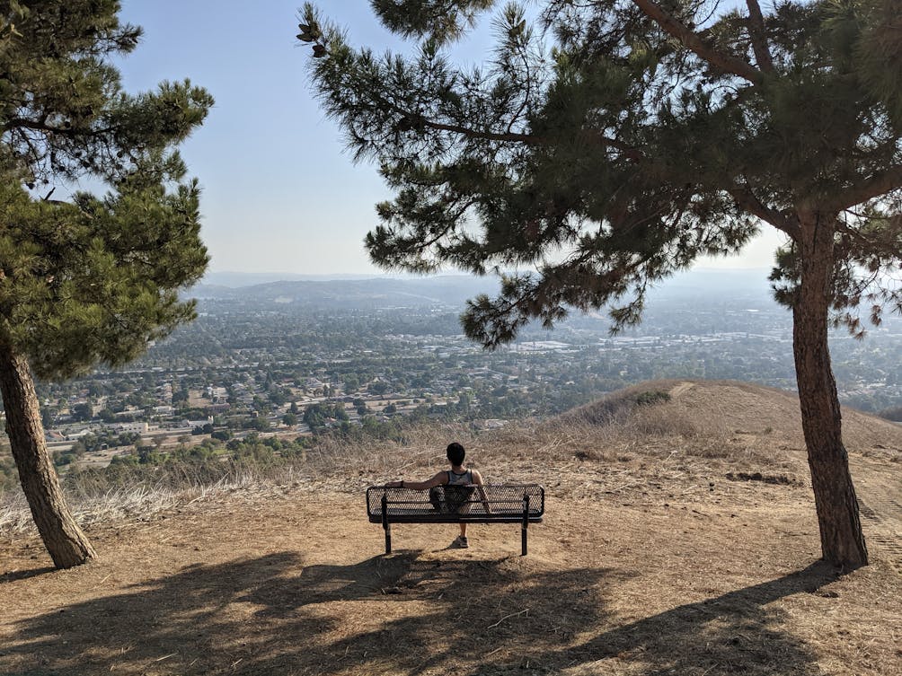 Person sitting at a bench at a highpoint overlooking the San Gabriels at Horsethief Canyon Park in San Dimas 