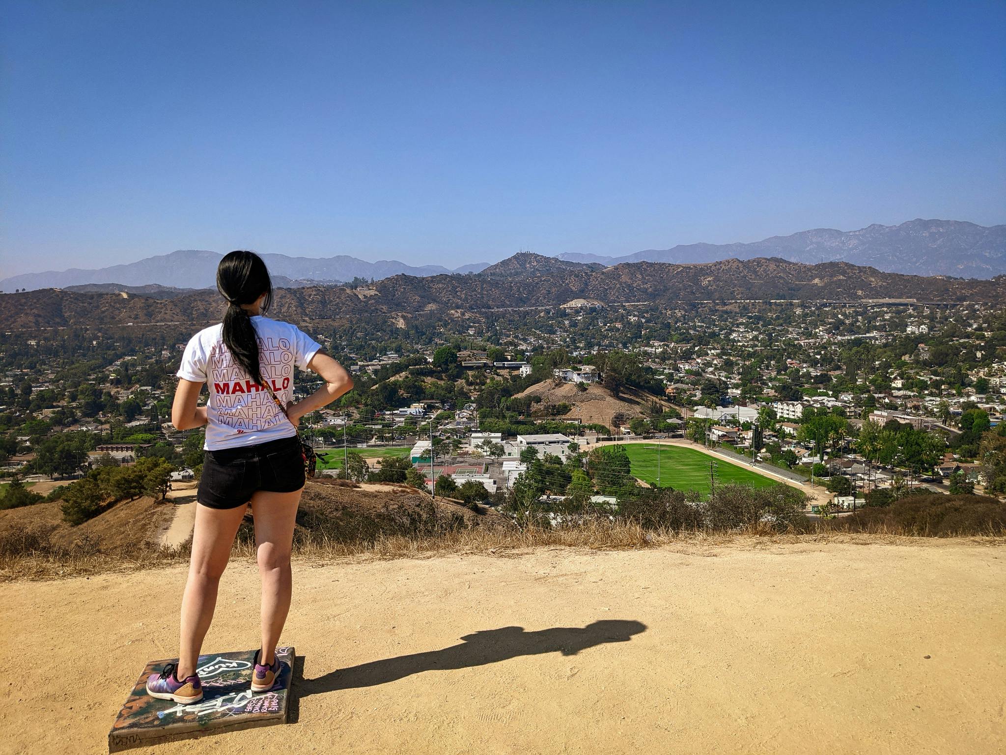 Hiker at the top of Fiji Hill overlooking the mountainous background in Los Angeles