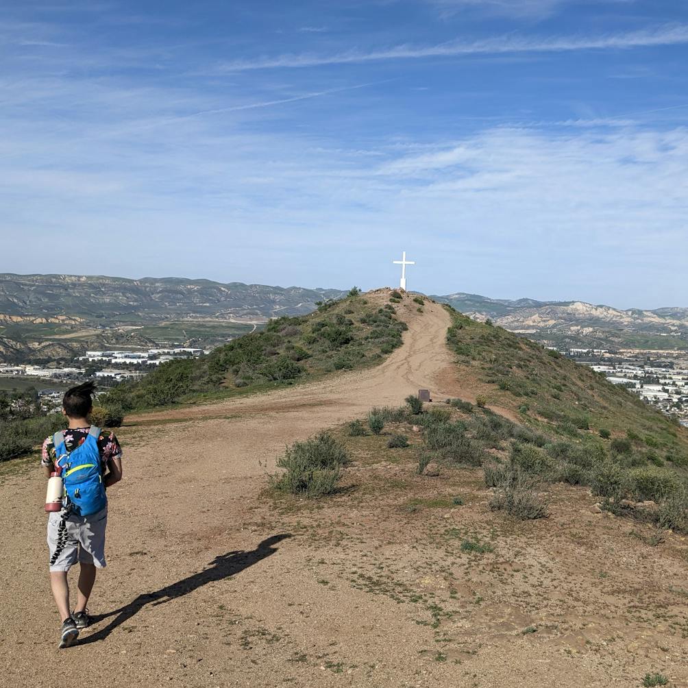 Hiker on a trail leading up to a giant cross at Mount McCoy in Simi Valley 