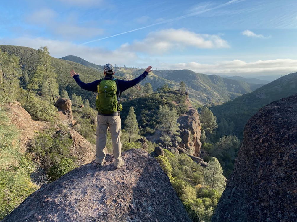 Person hiking a scenic trail overlooking the mountain scenery at Pinnacles National Park