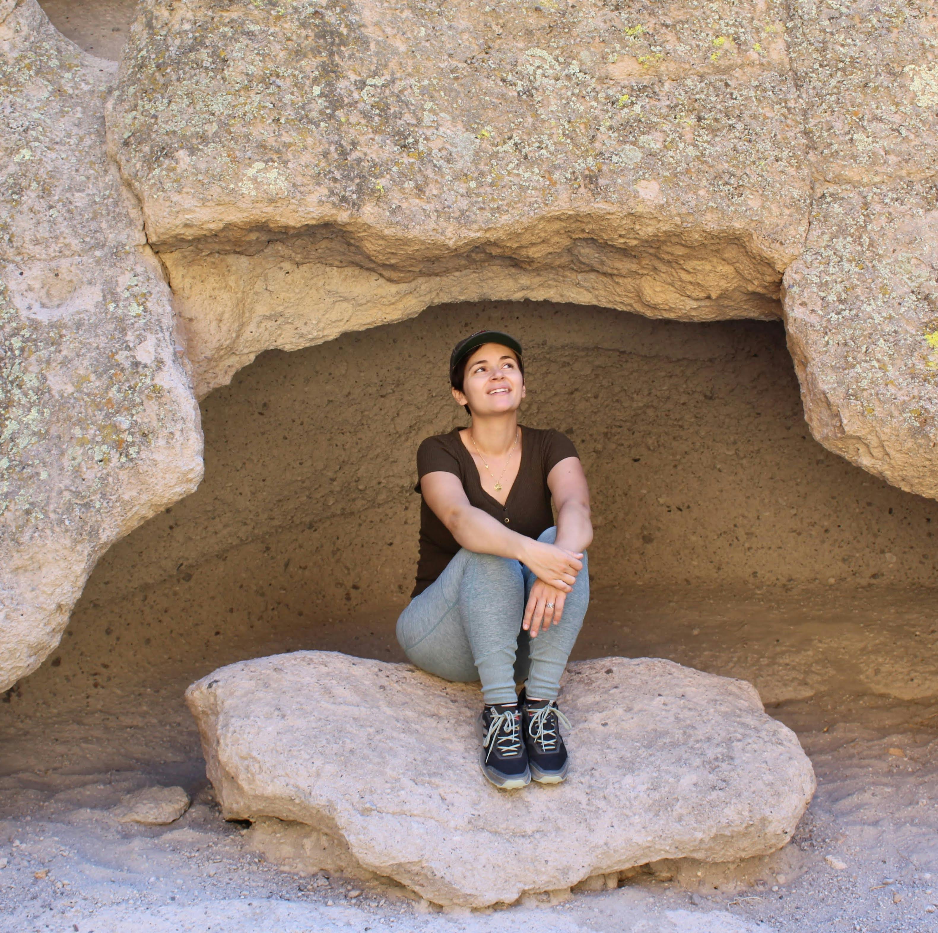 Hiker sitting on a large rock under a cavern in Hole in the Wall Rings Trail Mojave Desert 