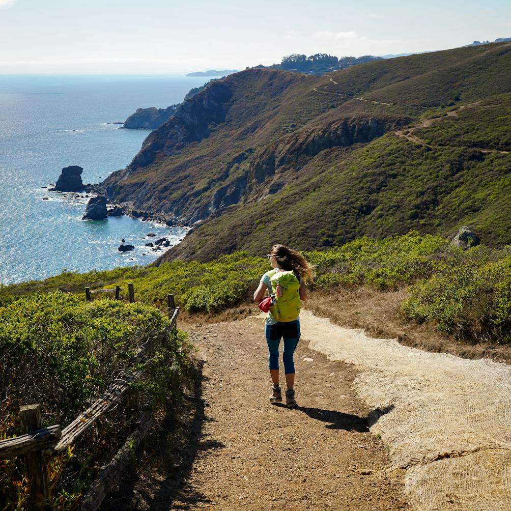 Woman hiking down the Coastal Trail in the Marin Headlands 