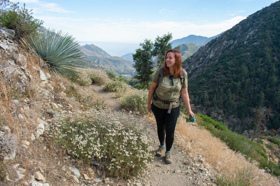 Woman hiking the Bear Canyon Trail with huge mountain views in the background at Mount Baldy in Los Angeles County