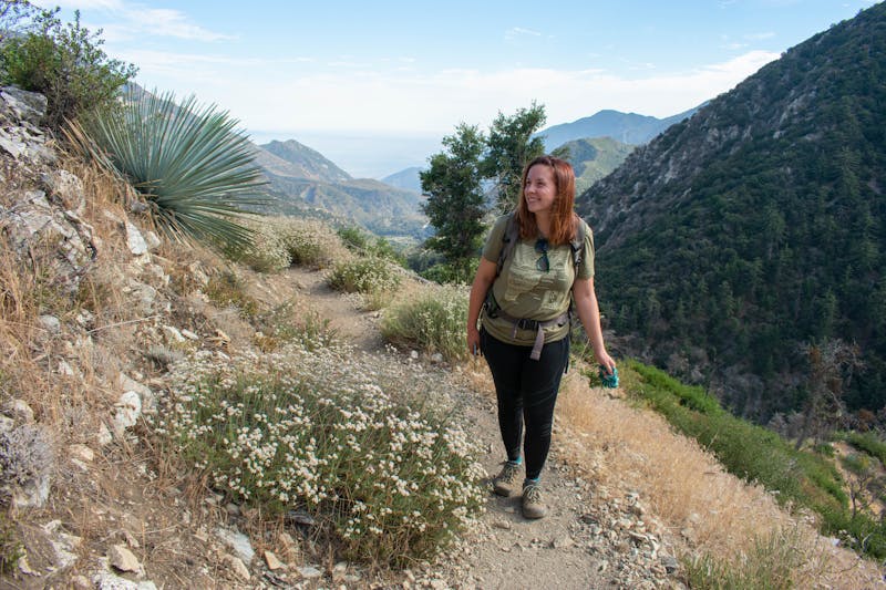 Woman hiking the Bear Canyon Trail with huge mountain views in the background at Mount Baldy in Los Angeles County 