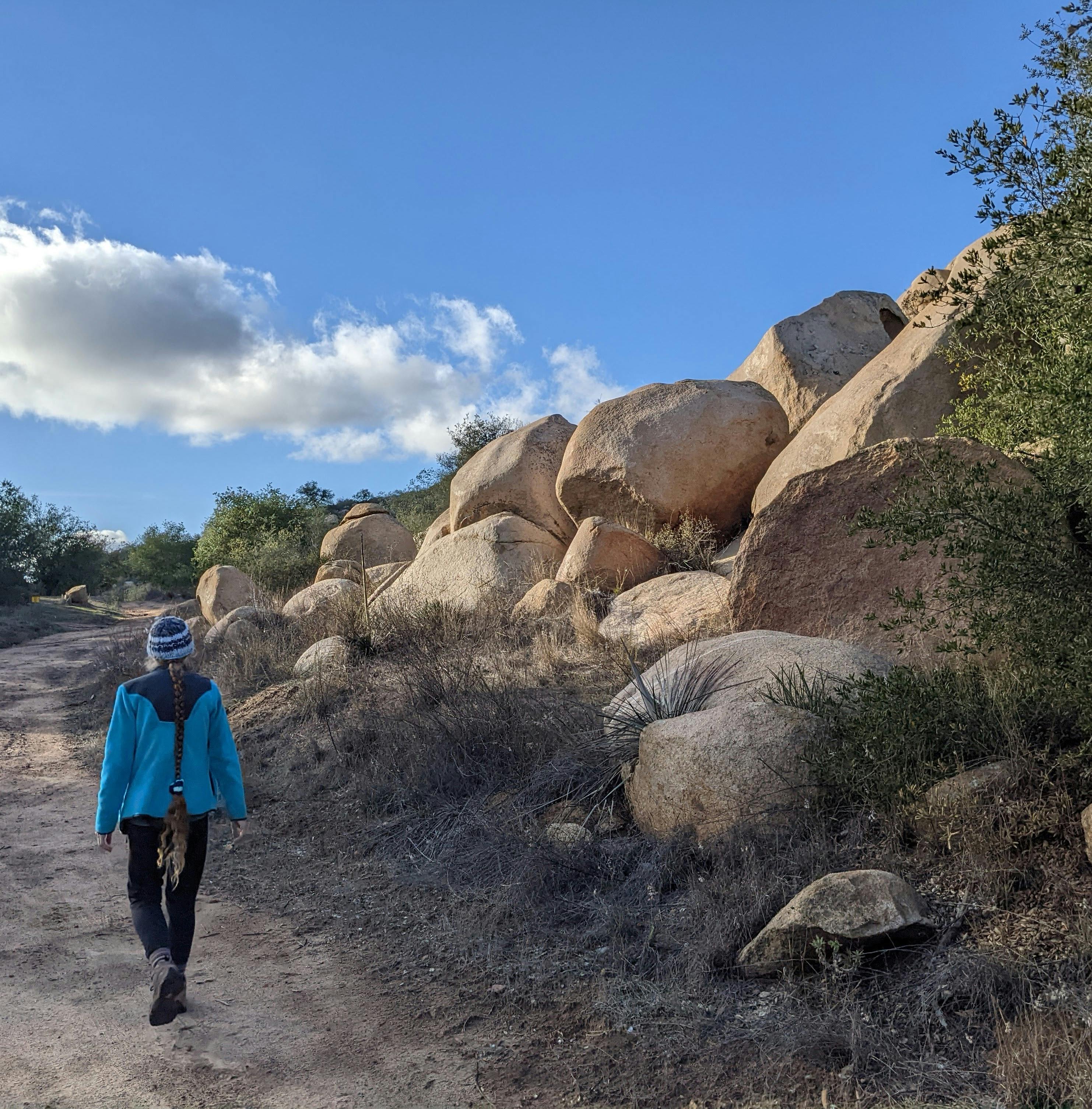 Hiker on a trail going past boulders at Daley Ranch in Escondido North San Diego County