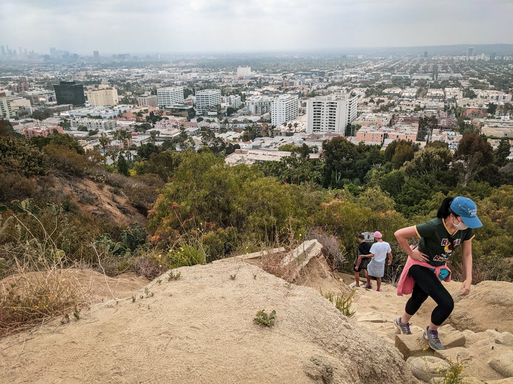 Hiker going uphill at Runyon Canyon with views of LA below in Los Angeles 
