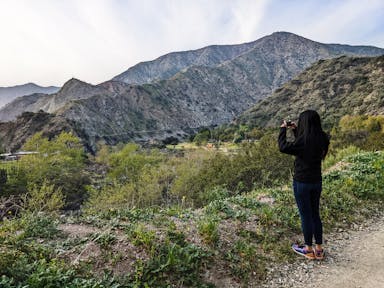 Hiker taking a picture of the San Gabriel Mountains on a trail at Azusa River Wilderness Park in Los Angeles 