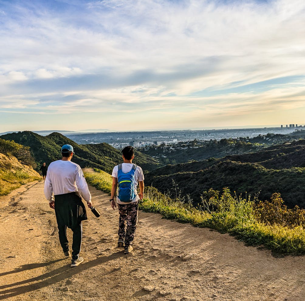 Two hikers on a trail in Los Angeles overlooking the city in Griffith Park 