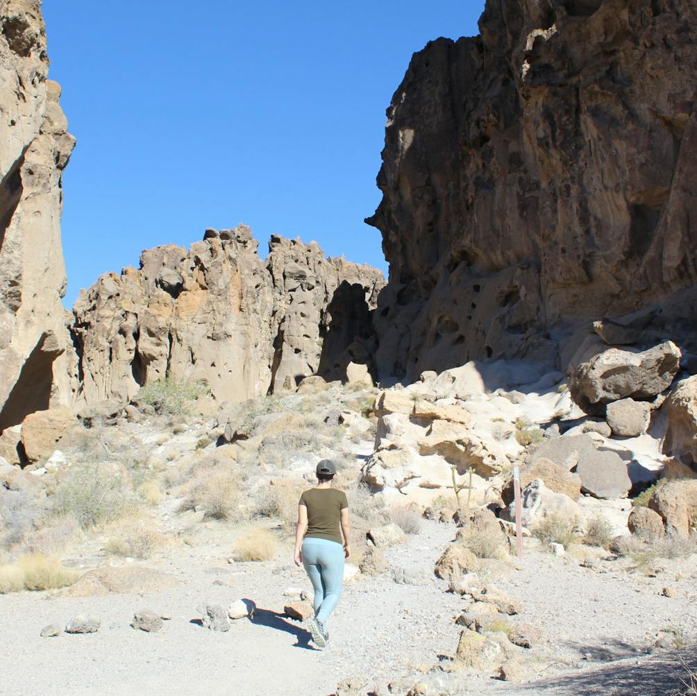Hiker heading up to hike through a canyon in Hole in the Wall Rings Loop in Mojave Desert 