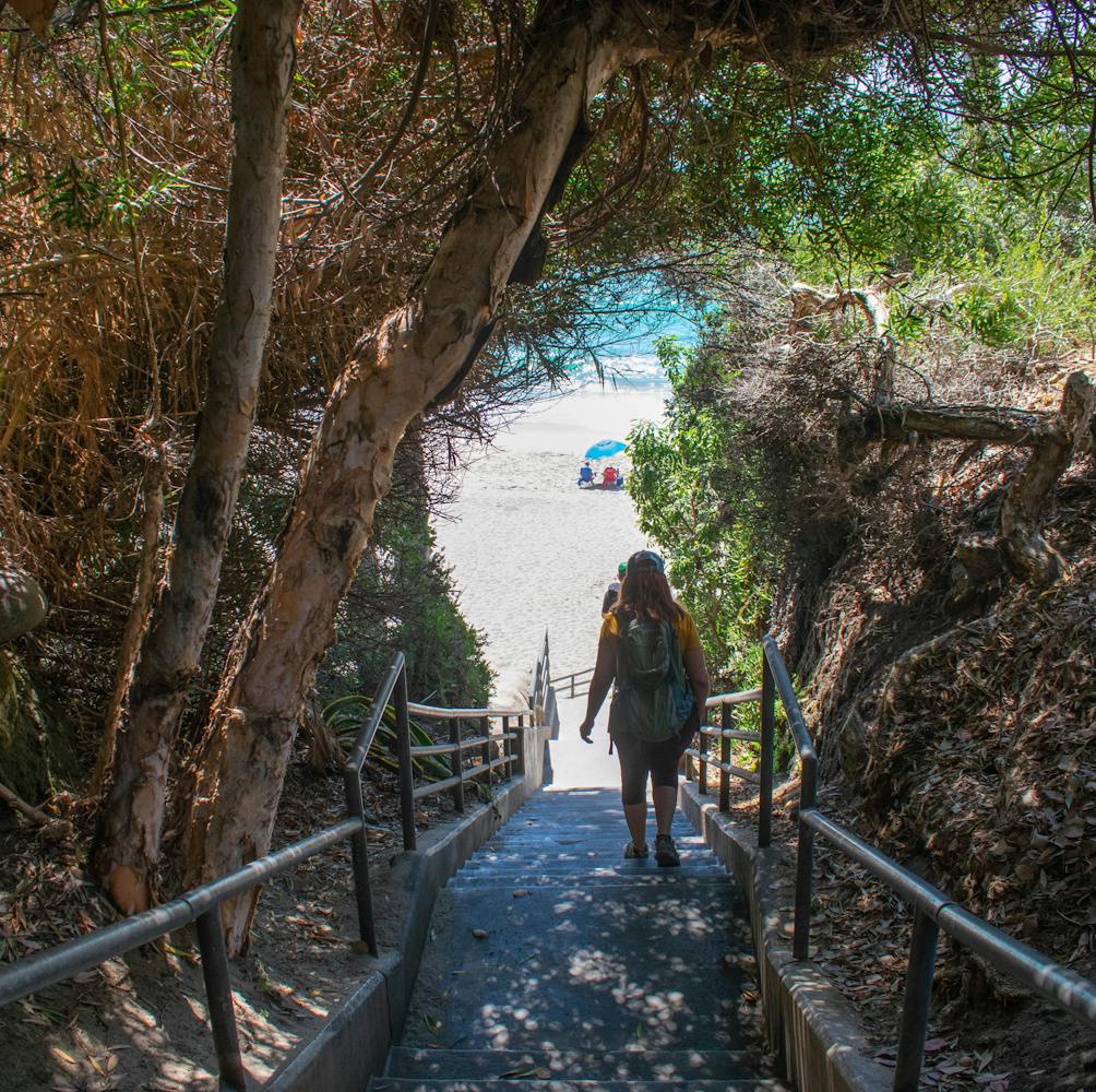 Hiker going down stairs towards Coast Royale Beach in Orange County