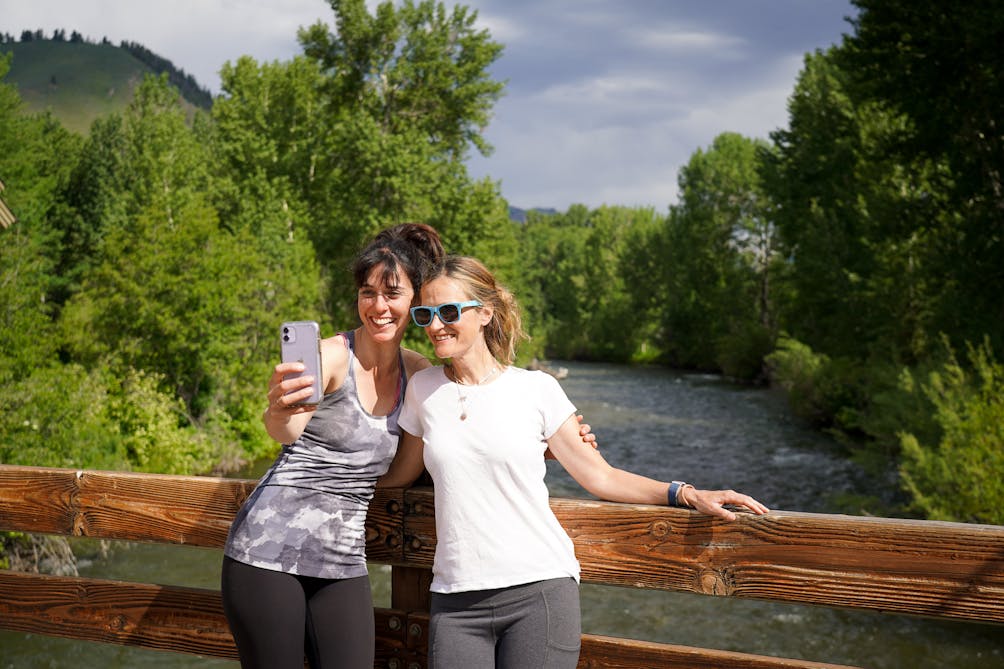 Two people taking a selfie on a bridge overlooking the river at River Run in Sun Valley 