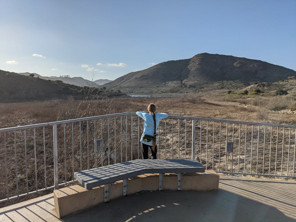 Woman standing at a bench area overlooking Lake Hodges at Lake Hodges Bicycle Pedestrian Bridge