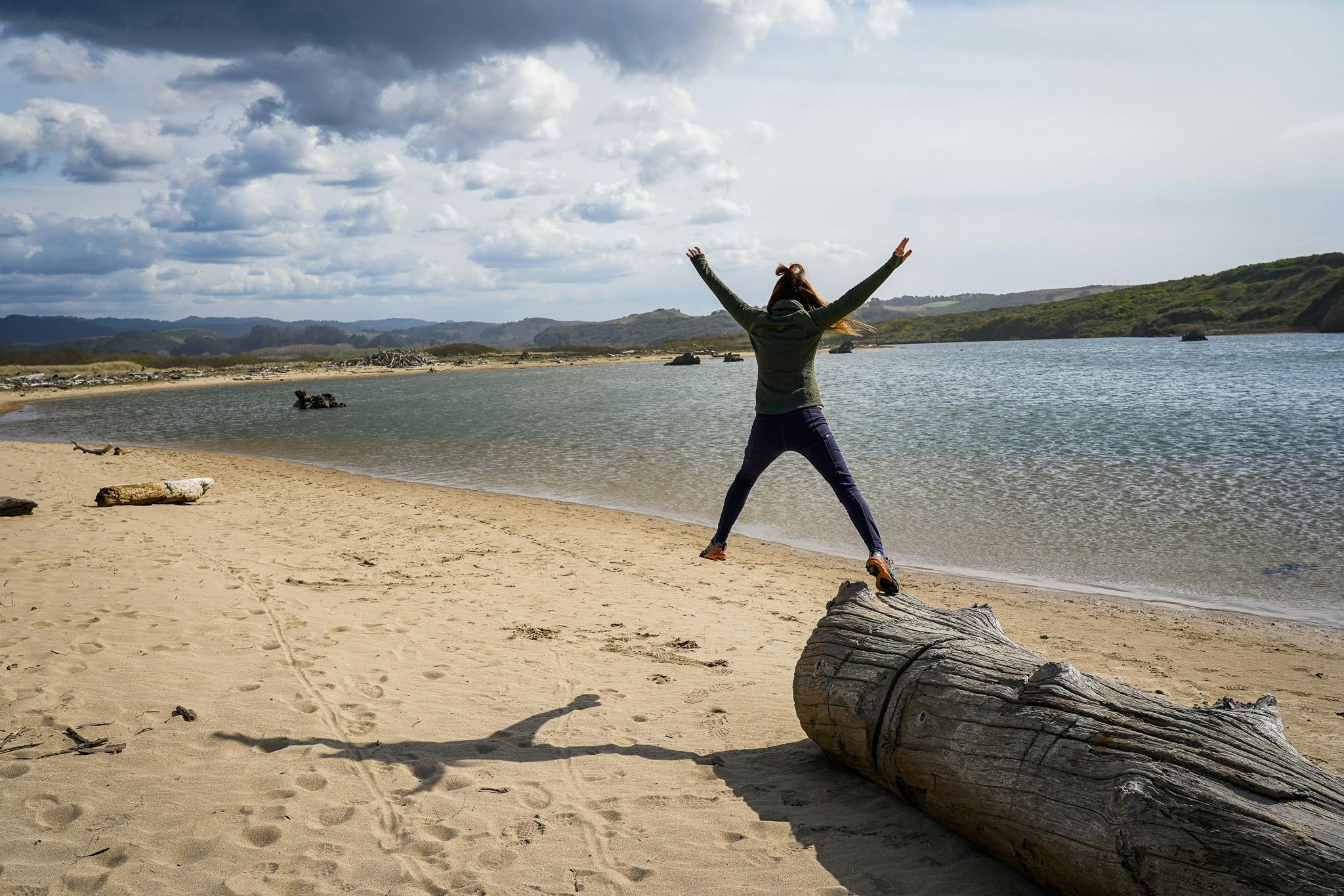 Woman jumping on the beach at Pescadero Marsh