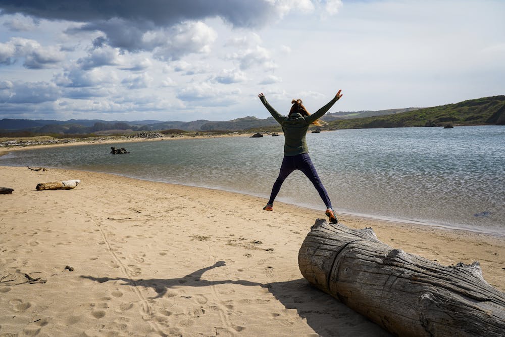 Woman jumping on the beach at Pescadero Marsh