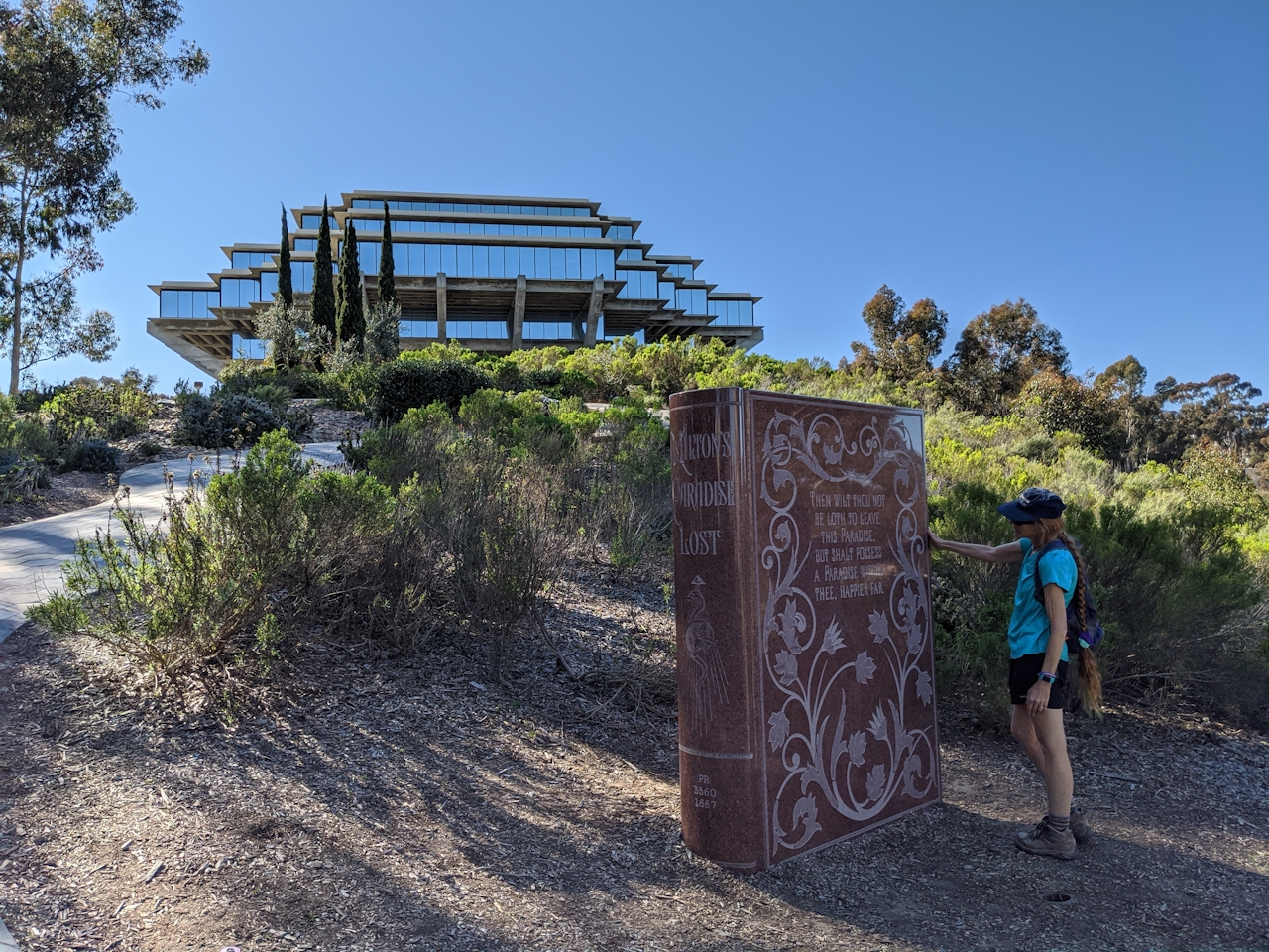 Woman standing at the sculpture of granite as the Paradise Lost Book at University of California, San Diego