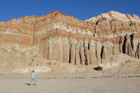 Hiker waving to camera in font of giant marbled sandstones at Red Rock Canyon State Park 
