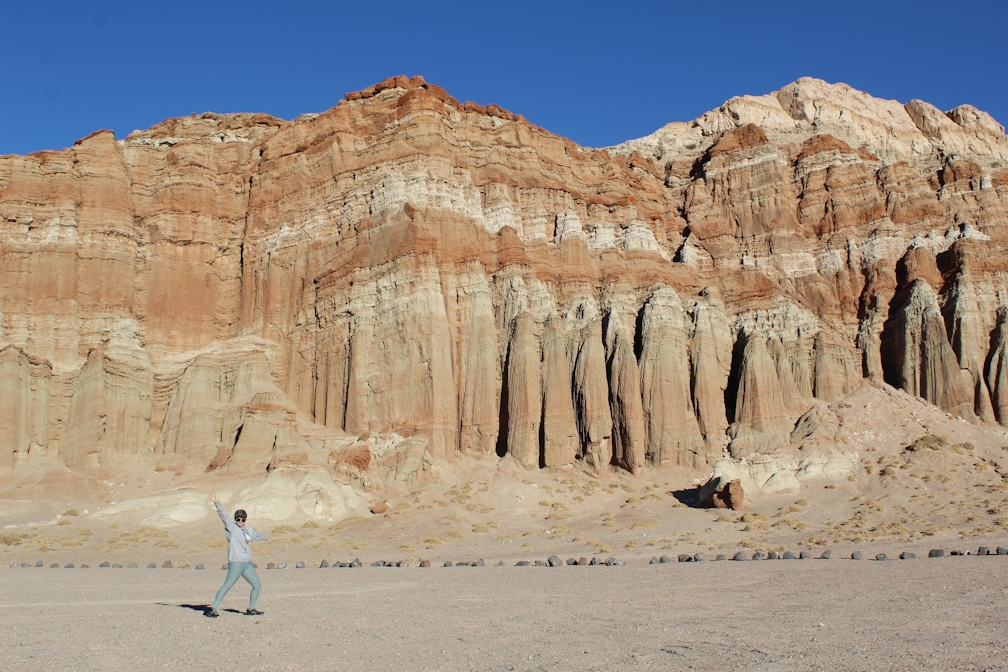 Hiker waving to camera in font of giant marbled sandstones at Red Rock Canyon State Park