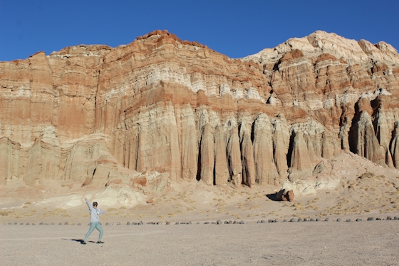 Hiker waving to camera in font of giant marbled sandstones at Red Rock Canyon State Park