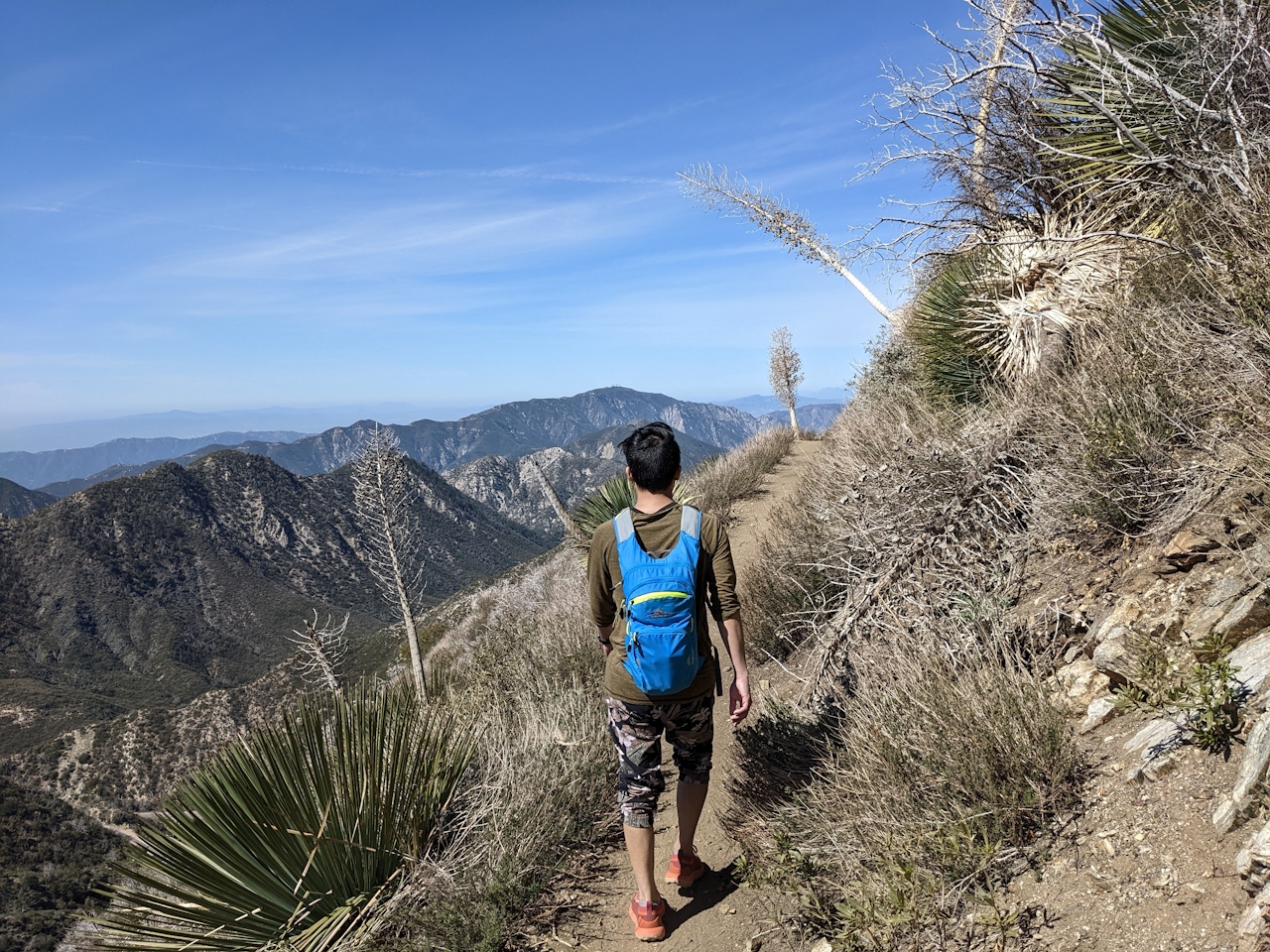 Hiker on a singletrack trail surrounded by the San Gabriel Mountains on the way to Strawberry Peak 