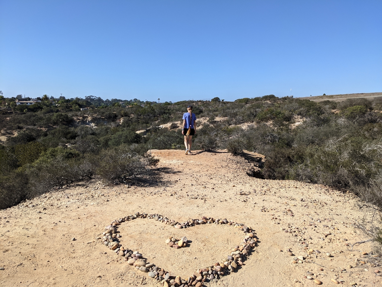 A hiker stands and surveys the scenery near a heart rock formation at Manchester Preserve in North San Diego County 