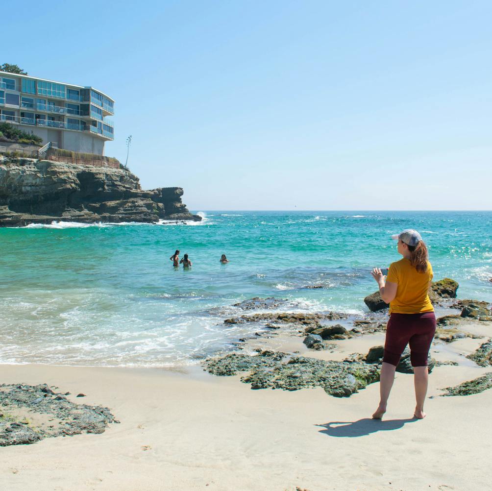 Woman standing at a turquoise beach cove at Coast Royale Beach in Orange County 