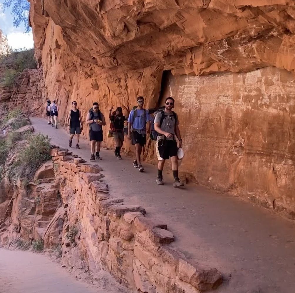 Group of friends hiking in a row along a red rock canyon wall in Zion National Park 