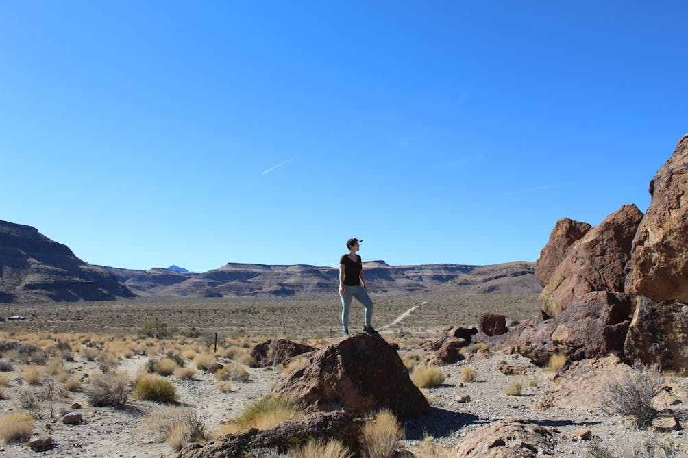 Hiker standing on a giant boulder overlooking the Mojave Desert 