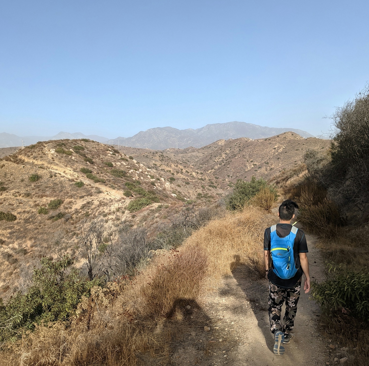 Hiker on a trail at Shadow Hills with views of the Verdugo Mountains 