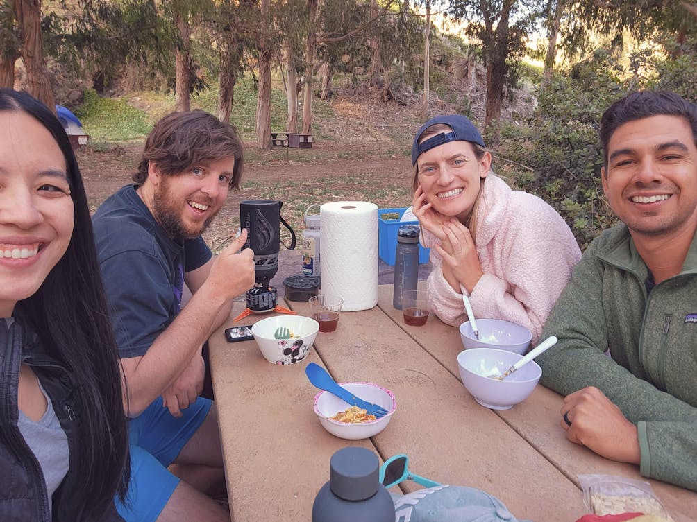 Four people sitting at a picnic table and smiling for the camera at Santa Cruz Island on Channel Islands National Park 