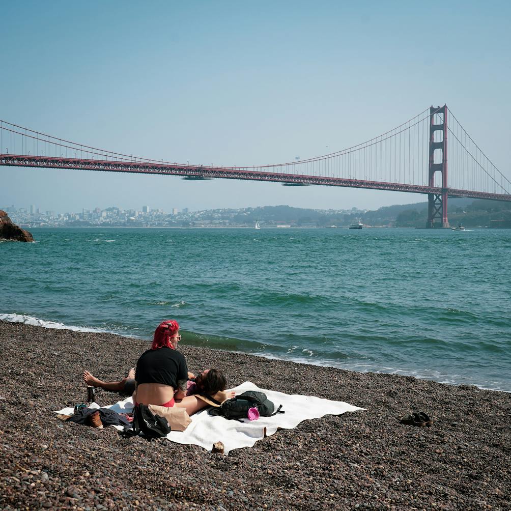 A few people relaxing on the beach at Kirby Cove with the Golden Gate Bridge in the background 