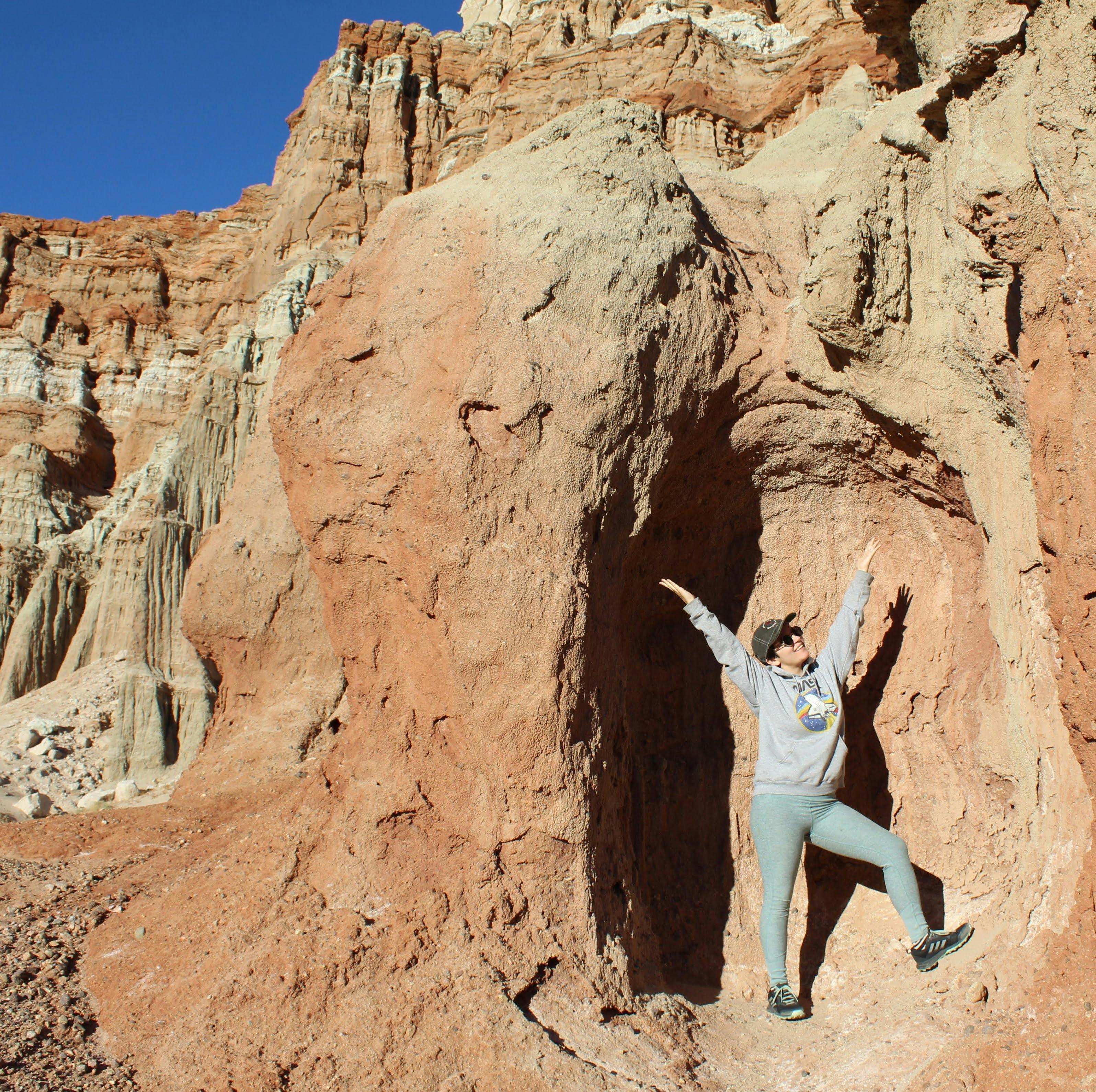 Person posing inside a cavern pocket at Red Rock Canyon State Park 