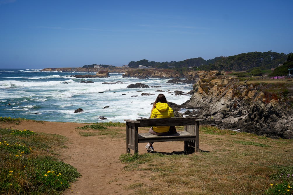 woman at a bench overlooking Mendocino coast