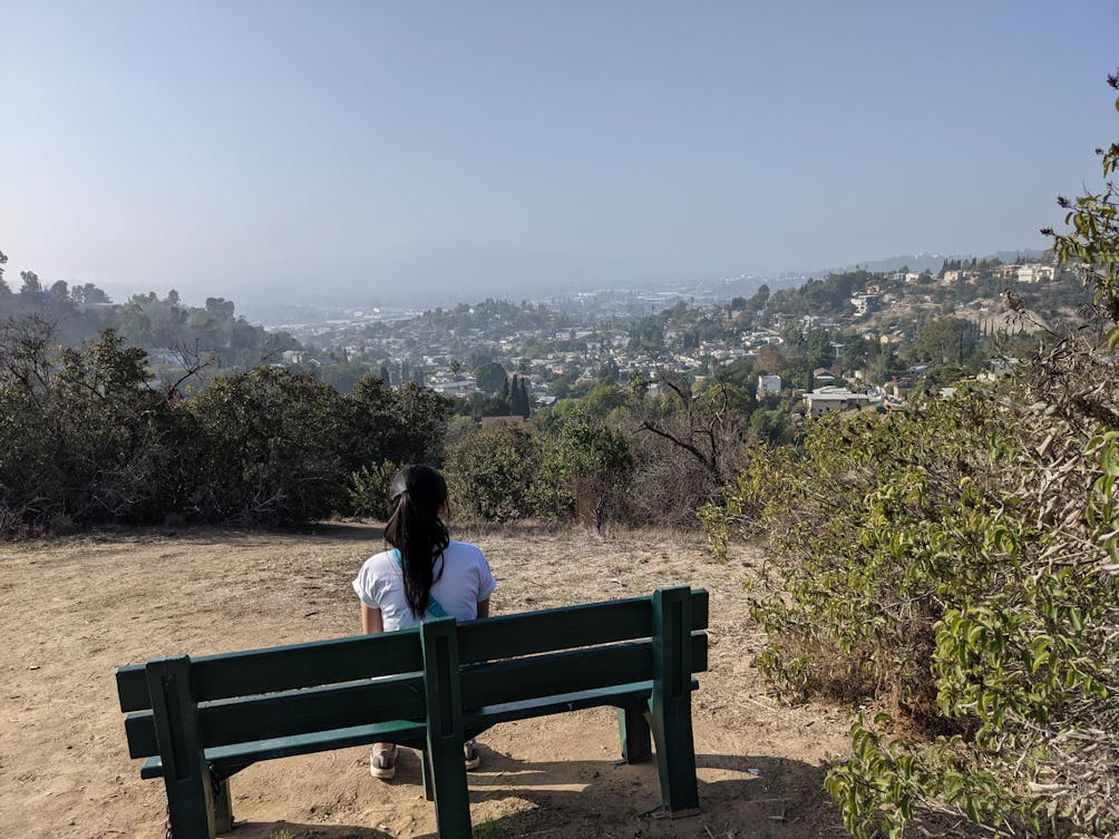 Woman sitting on a bench and taking in the view at a hike in east LA Mount Washington