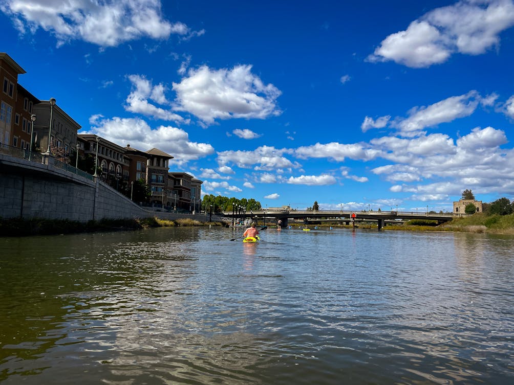 Paddler on the Napa River passing by downtown Napa and Stone Brewing