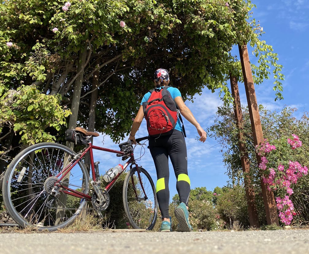 Woman with her bike at entering a garden along Guadalupe River Trail in San Jose