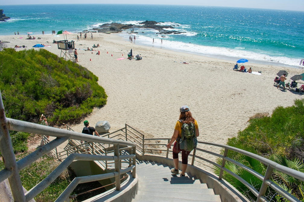 Woman hiking down the stairs to Coast Royale Beach in Orange County
