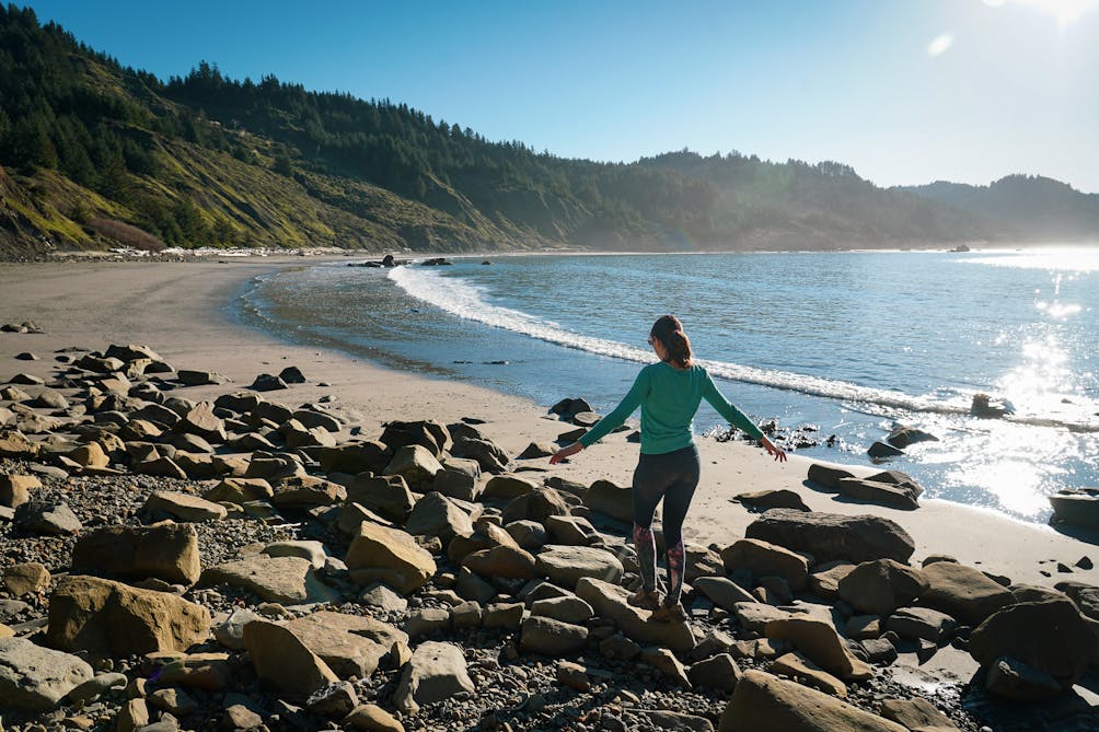 A woman crosses over some rocks at Hunters Cove hike-in beach at Cape Sebastian on the Oregon Coast