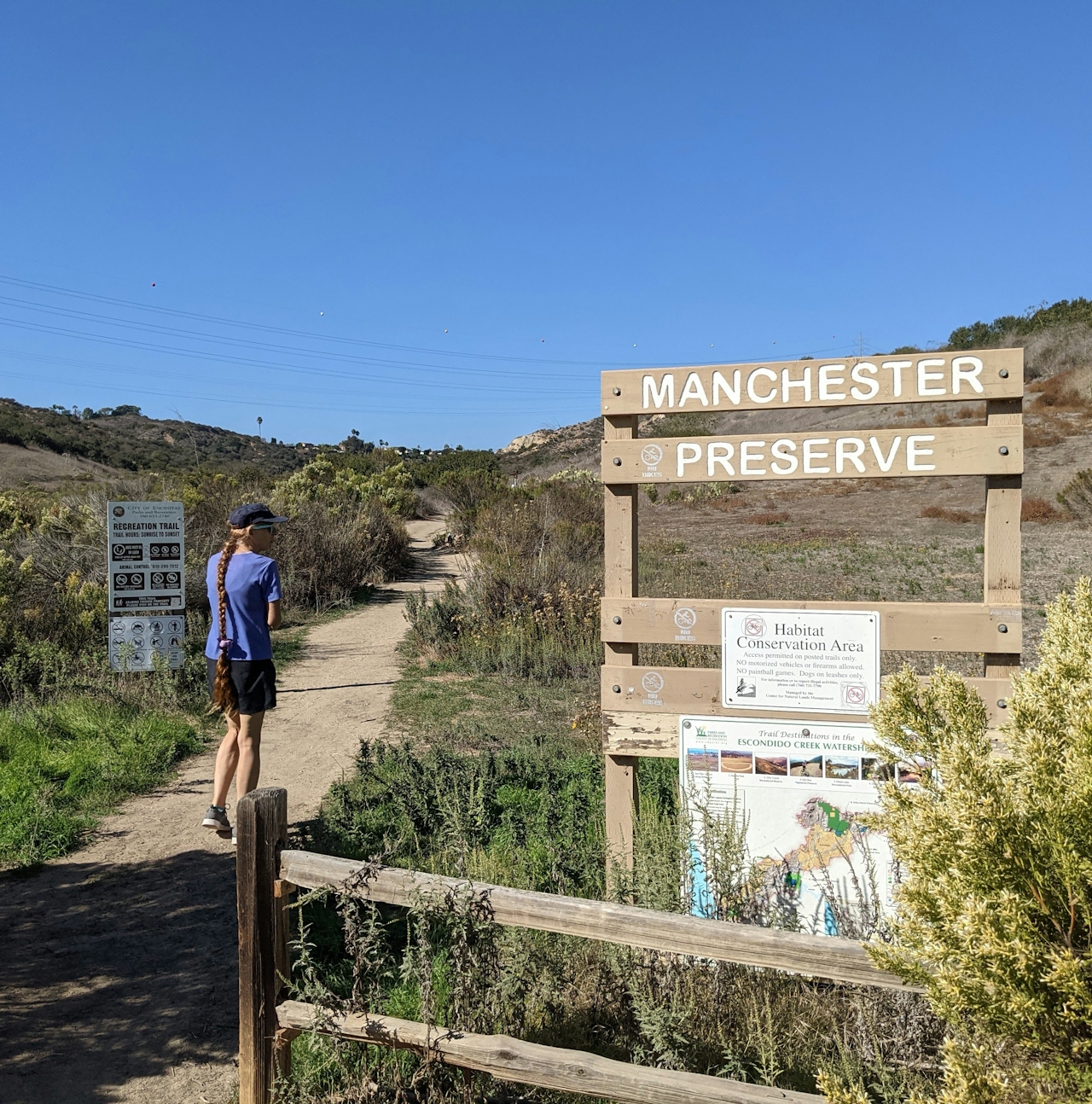 A hiker walks past the sign for Manchester Preserve in North San Diego County 