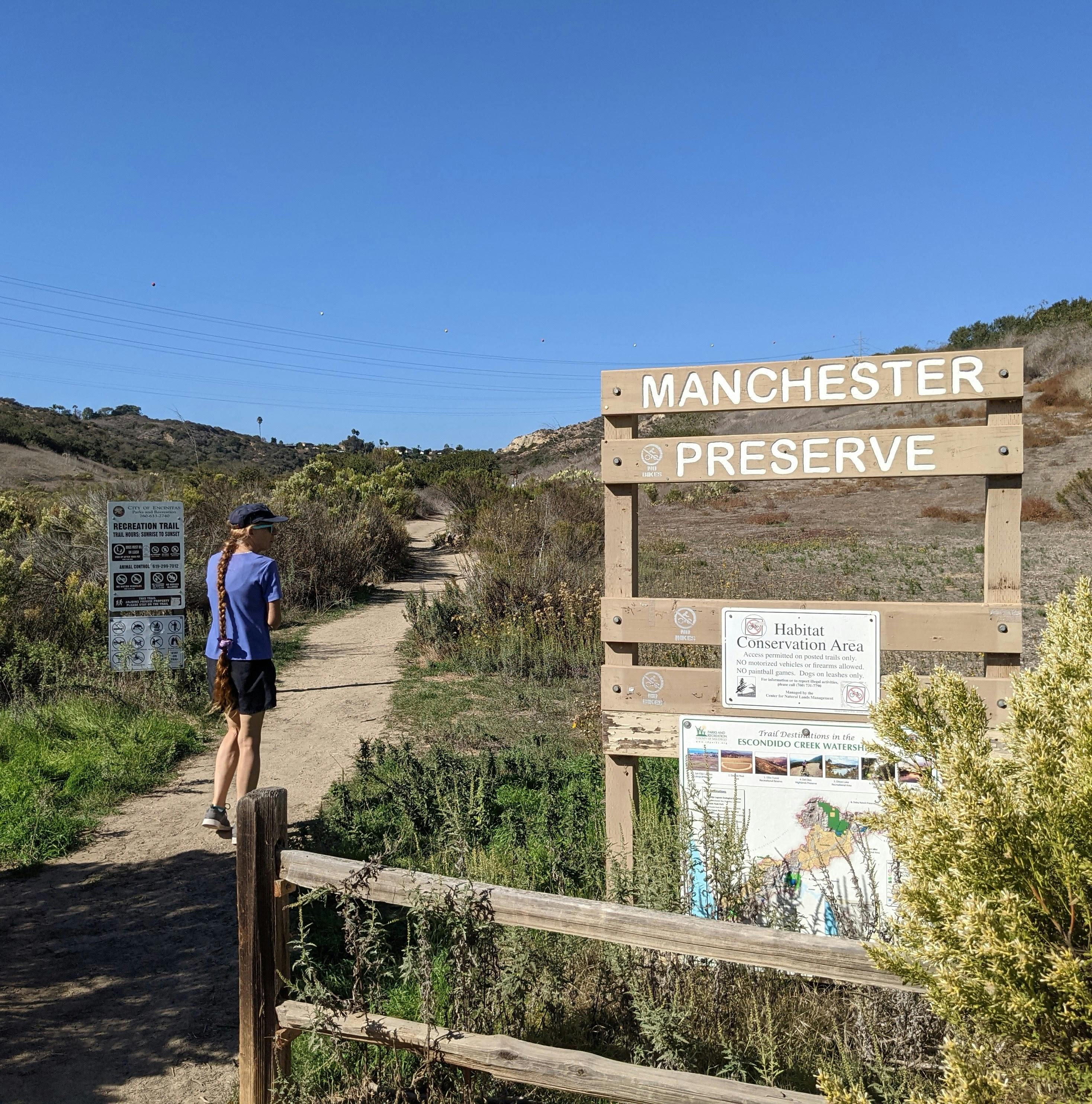 A hiker walks past the sign for Manchester Preserve in North San Diego County 