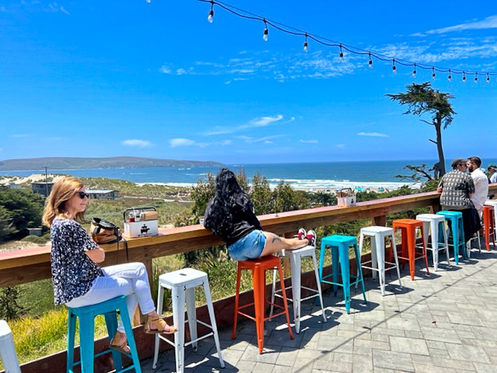 People sitting on the orange, white, and blue chairs at Dillon Beach Resort's Coastal Kitchen outdoor patio in Marin 