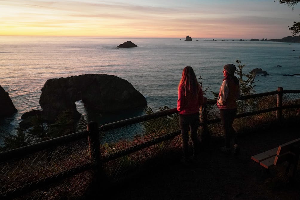 Two people at a viewing platform overlooking Arch Rock. on the Oregon Coast 