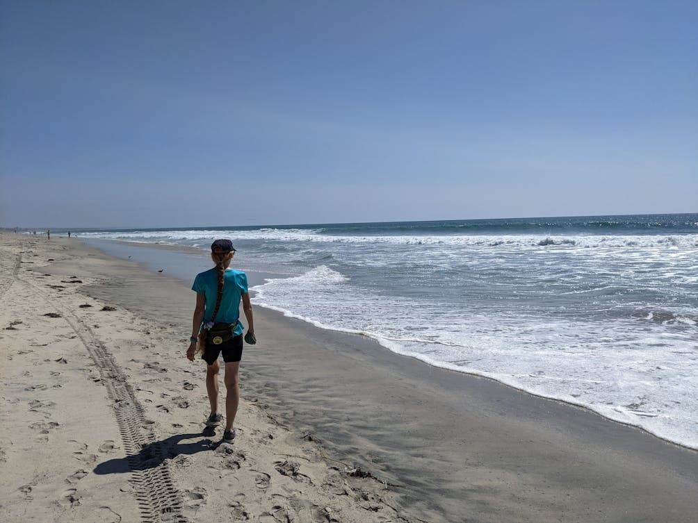 Woman walking on the ocean shoreline at Carlsbad City Beach 