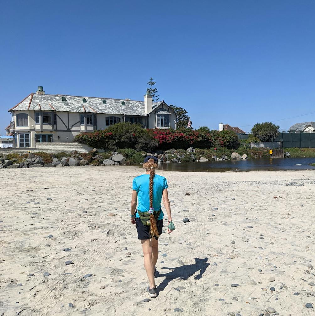 Woman walking towards a large house on Carlsbad City Beach in San Diego County 