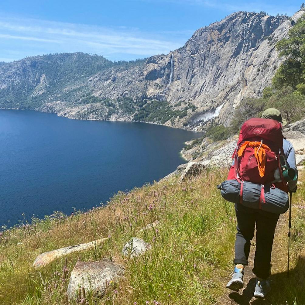 Backpacker on trail next to lake in Hetch Hetchy Yosemite 